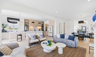 An open-concept living area with a fireplace. On one side is a full kitchen, on the other is a dining area by the stairs.